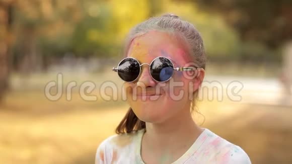 假期的彩色颜料一个戴眼镜的女孩把蓝色的彩色粉末举到空中有趣的是视频的预览图