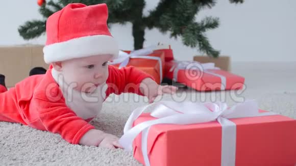 圣诞节的概念穿着圣诞老人服装可爱的宝宝看着礼物视频的预览图