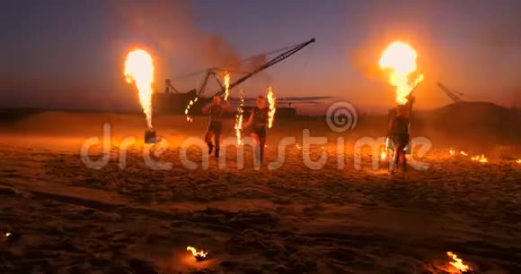 一群男人和女人在夜晚的沙滩上表演火和塔吊的背景视频的预览图