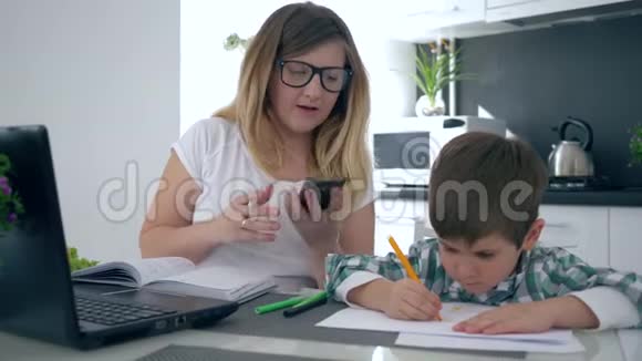 在家工作母亲用手机说话儿子在她身边玩耍视频的预览图