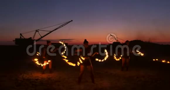 一群男人和女人在夜晚的沙滩上表演火和塔吊的背景视频的预览图