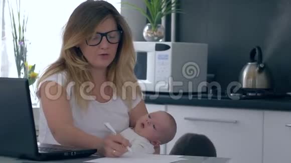 紧张的精神崩溃抱着婴儿的母亲尖叫着她的儿子他正在家里干涉工作视频的预览图