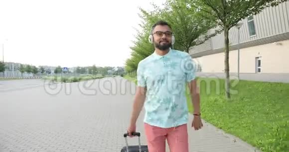 带着非洲游客走向镜头穿着t恤短裤和太阳镜的年轻人正把行李拖到视频的预览图