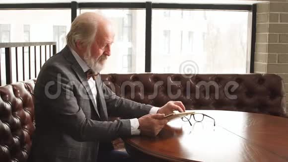时尚资深男士正在工作场所观看平板电脑上的视频视频的预览图