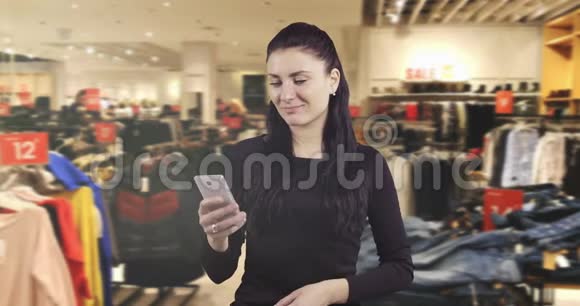 一位深受感动的年轻黑发女子正在购物中心的手机上阅读一条信息视频的预览图