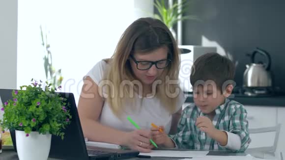 母亲帮助儿子用彩色毡尖笔画坐在厨房里视频的预览图