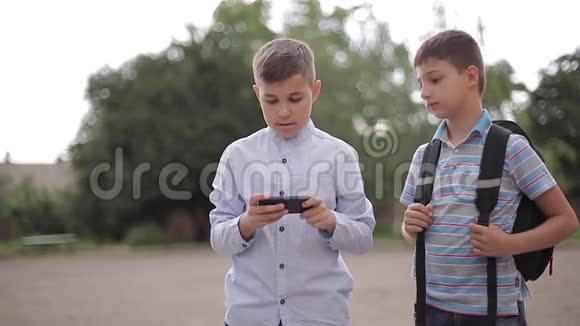 两个男孩放学后玩网络游戏小男孩微笑用电话视频的预览图