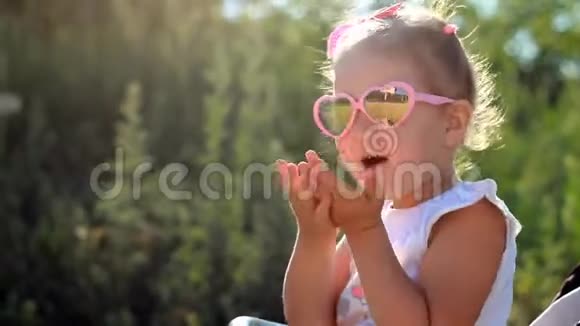 戴着太阳镜的孩子坐在婴儿车里在日落时分送上飞吻视频的预览图