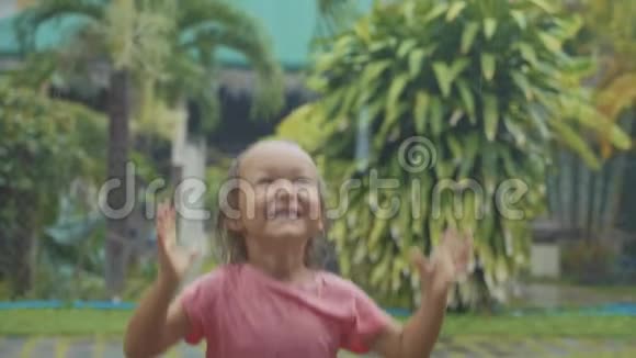 一幅5岁的小女孩在热带雨中嬉戏慢动作的肖像视频的预览图