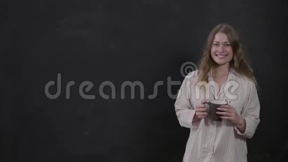 可爱的女孩穿着超大的白色衬衫手里拿着咖啡衬衫上贴着生活方式设计师的标签视频的预览图
