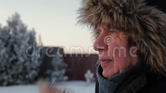 穿着夹克和皮帽的老人在冬天用手帕擦他的鼻子视频的预览图