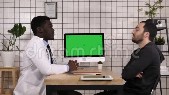 医生和他的男性病人谈话白色显示器视频的预览图