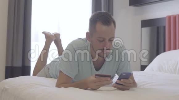 男人用信用卡和智能手机成功付款躺在床上视频的预览图