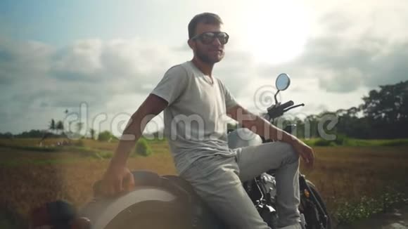 戴眼镜坐在摩托车上的年轻人的肖像视频的预览图