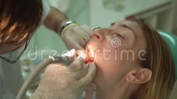 在诊所使用特殊牙科设备的牙科医生与美丽的女性病人视频的预览图