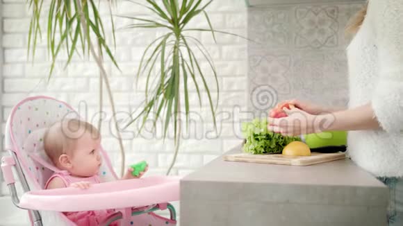 可爱的孩子看着妈妈做饭女性烹饪蔬菜视频的预览图