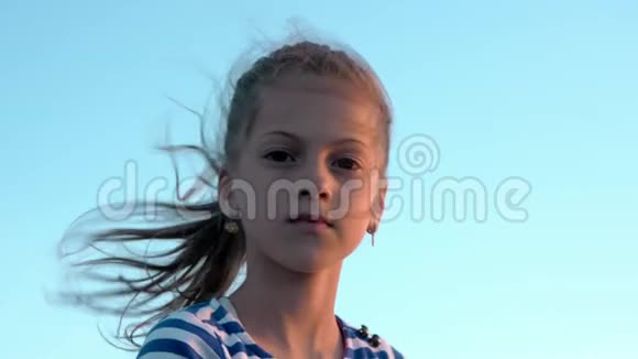 有魅力的小女孩的肖像穿着条纹衬衫天空背景发落日视频的预览图