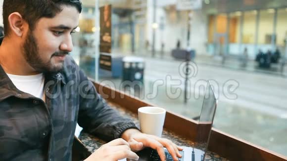 年轻的黑发拉丁西班牙裔男子正在使用电脑坐在咖啡馆录像片段视频的预览图