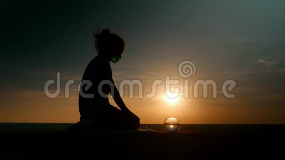 剪影小女孩在日落时的海景背景下看着小水族馆看着打架的鱼概念放松视频的预览图