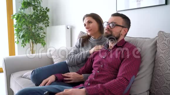 幸福的一对夫妇在新房子的沙发上看电视一起看电影休闲概念视频的预览图