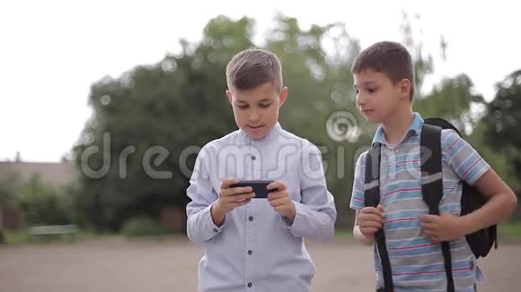 两个男孩放学后玩网络游戏小男孩微笑用电话视频的预览图