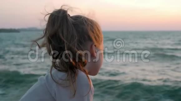 小女孩看着日落时海上刮风的日子思想观念集中生活方式视频的预览图