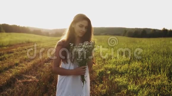 站在田野里的女人手里捧着一束野花夕阳下披散的长发微笑着视频的预览图
