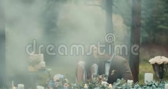 在雾蒙蒙的森林里浪漫的约会中恋爱中的一对漂亮的情侣在轻轻地接吻装饰桌和蜡烛视频的预览图