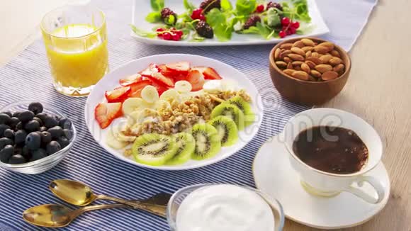 健康早餐来自梅斯利格拉诺拉新鲜水果猕猴桃草莓浆果酸奶果汁和咖啡视频的预览图