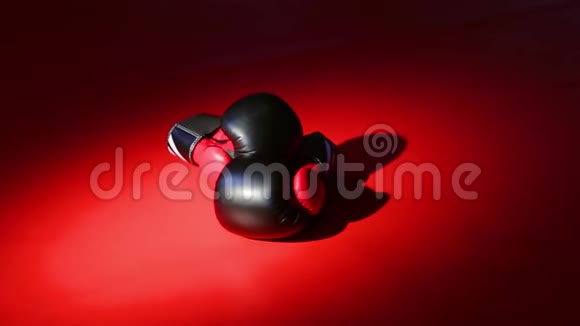 相机运动黑色和红色拳击手套躺在红色的地板上在美丽的人造光线下视频的预览图