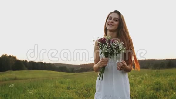 日落时分鲜花盛开的快乐女人在田野里奔跑在草地上享受和欢笑视频的预览图