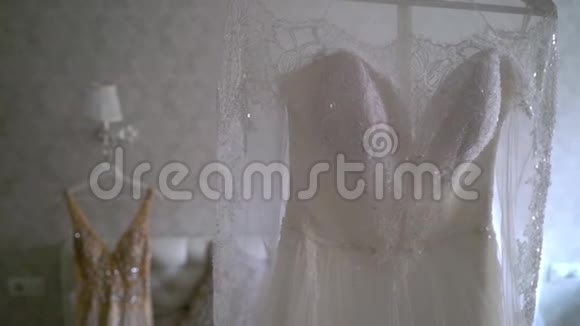 两件豪华婚纱挂在卧室里白色和金色令人惊叹的新娘蕾丝礼服的剪影视频的预览图