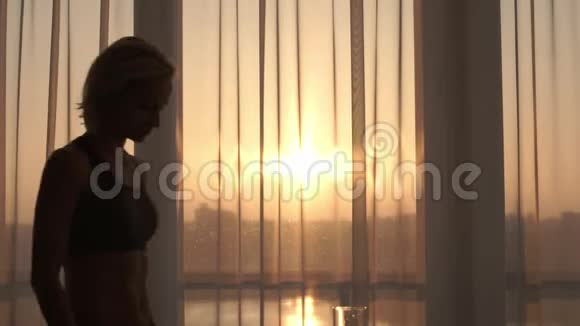 阳光明媚的早晨运动的女人在家里喝水视频的预览图