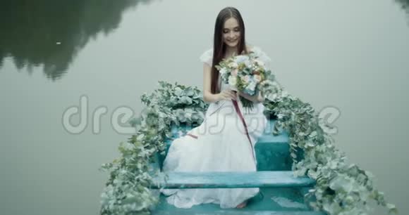 美丽的神秘微笑的黑发女子捧着迷人的花束漂浮在装饰着的花朵上视频的预览图