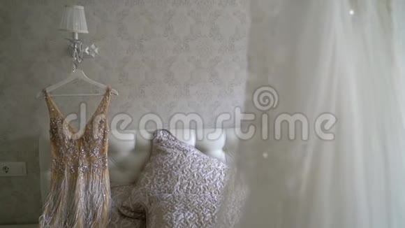 两件豪华婚纱挂在卧室里白色和金色令人惊叹的新娘蕾丝礼服的剪影视频的预览图