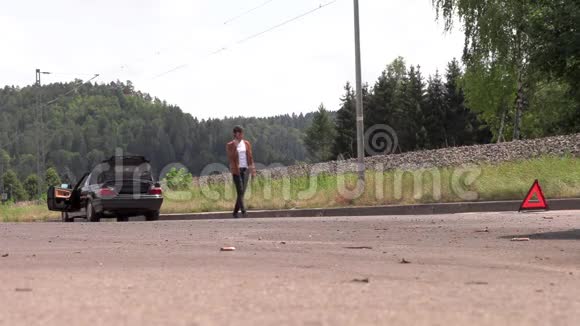 一个年轻人在一辆破车附近打电话视频的预览图