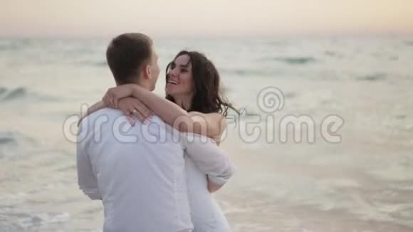 在大海的背景下一对美丽的新婚夫妇在大海的背景下温柔地拥抱着这对幸福而情绪化的夫妇的肖像视频的预览图