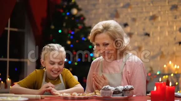 退休女性和女孩看着圣诞饼干和拥抱快乐的回忆视频的预览图