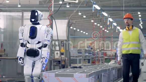 一名工人在工厂地板上用平板电脑控制机器人视频的预览图