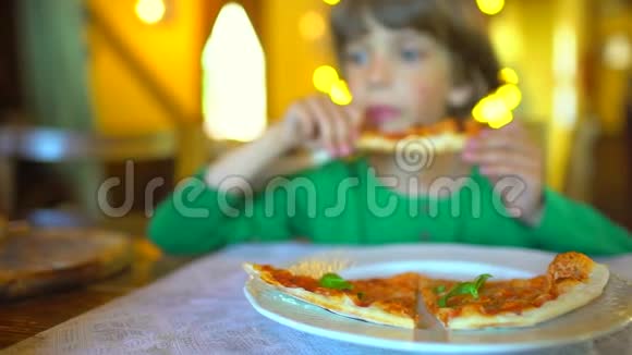 一个小孩子在快餐店吃披萨可爱有趣的白种人小男孩吃美味的意大利画视频的预览图