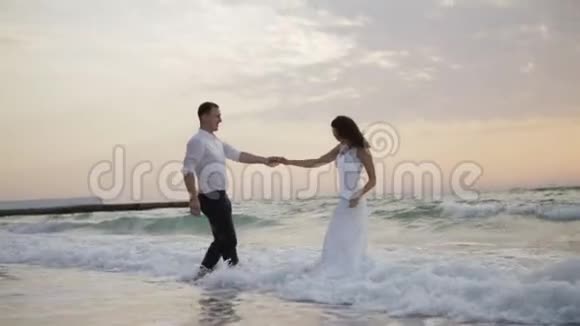 浪漫的概念欢乐迷人的新婚夫妇温柔地拥抱和享受日落时的大海视频的预览图