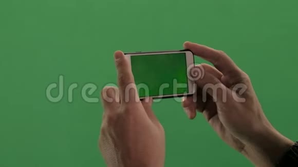 在绿色背景上有小玩意的人的手的特写他在手机上拍照或拍摄视频视频的预览图