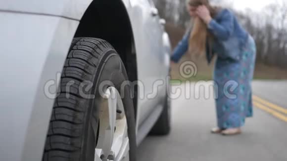 女人在路上检查她的越野车后面的轮胎是否有问题视频的预览图