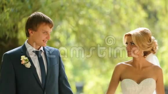 漂亮的新婚夫妇穿着时髦的布在阳光明媚的公园里温柔地接吻视频的预览图