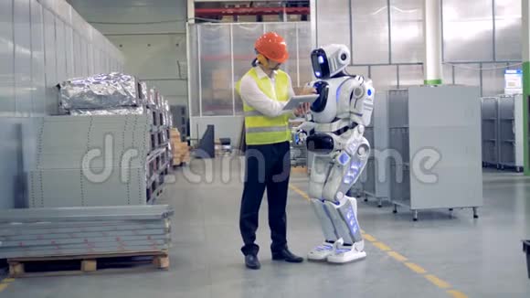 一名工厂工人向机器人展示在工业工厂该做什么视频的预览图