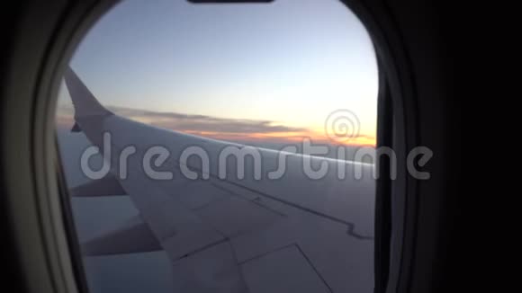 从飞机窗口日落观橙色的太阳飞机的翅膀黑暗的天空和云彩视频的预览图