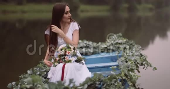 年轻可爱的黑发长发少女正拿着花束漂浮在雾蒙蒙的神秘小船上4K录像视频的预览图