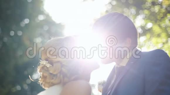 在阳光下亲吻新婚夫妇可爱的新婚夫妇在公园里温柔地摩擦鼻子视频的预览图