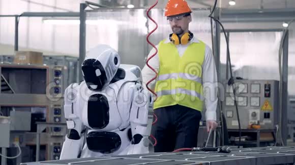 一个工厂工人打开机器人控制它视频的预览图