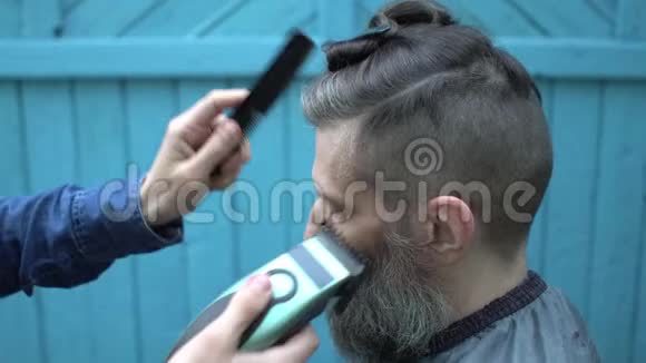 美丽的女理发师在露天理发厅用电动剃须刀理发视频的预览图